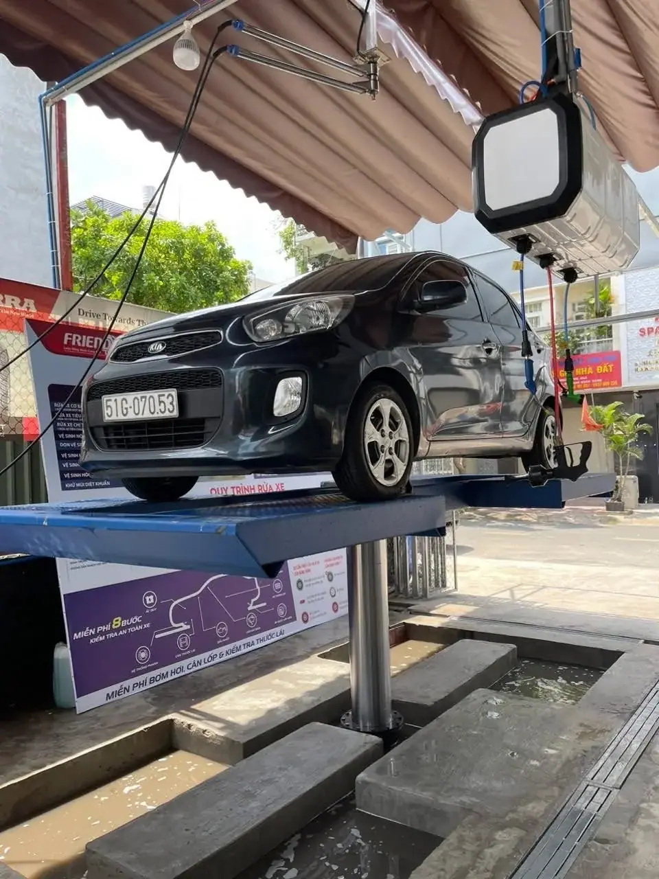 Cầu nâng 1 trụ rửa xe ô tô du lịch lắp âm nền đang nâng xe Kia Morning tại trạm rửa xe