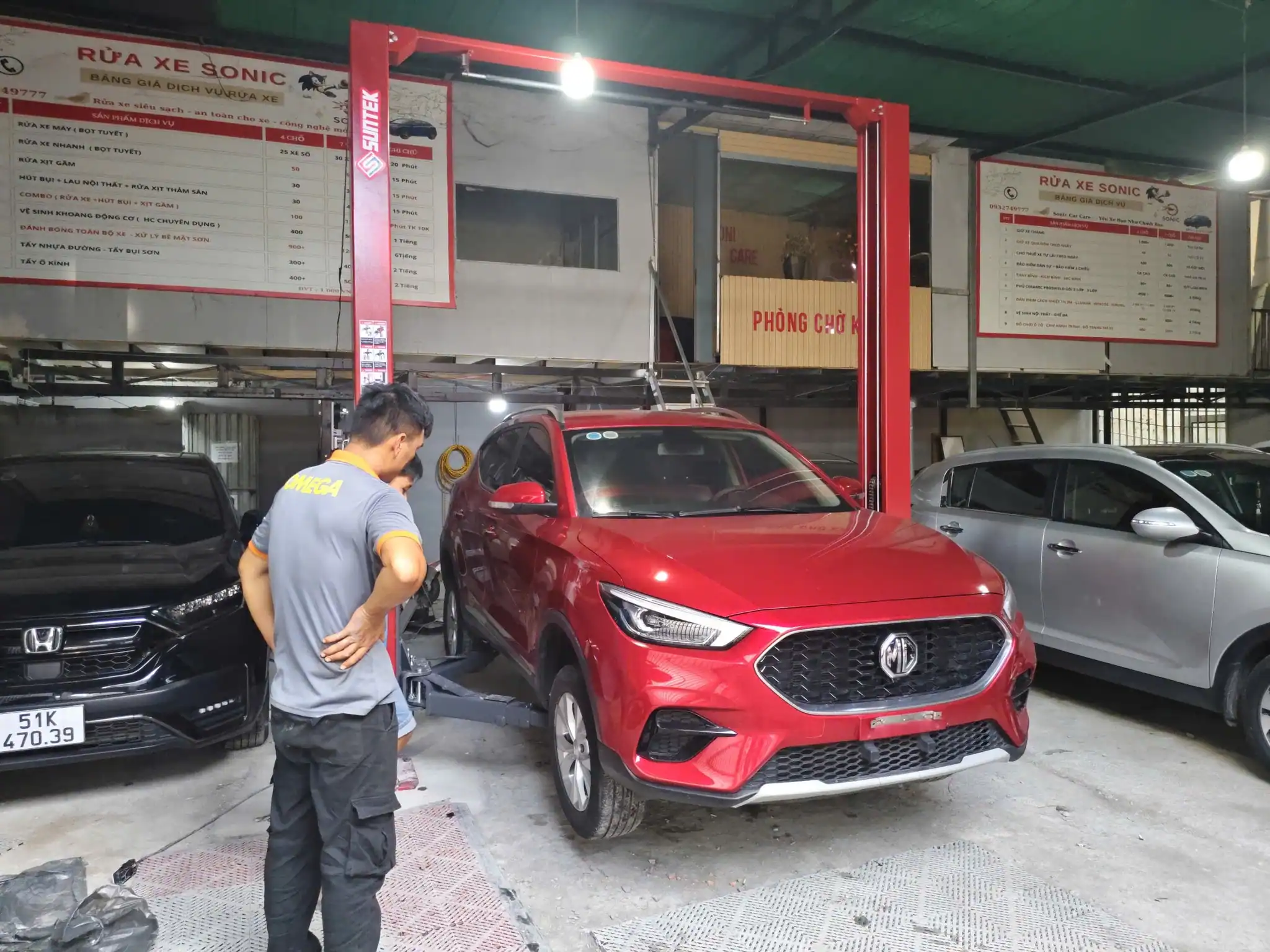 Cẩm Nang Lựa Chọn Cầu Nâng 2 Trụ Từ A-Z Dành Cho Người Mới Mở Gara 18 Kỹ thuật viên căn chỉnh tay vươn vào điểm đỡ của xe