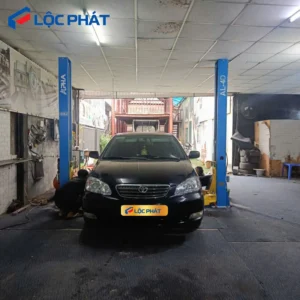 Cầu nâng 2 trụ cổng dưới (Hình thực tế đang nâng xe ô tô con màu đen trong gara