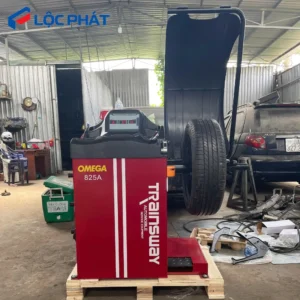 Máy cân bằng lốp ô tô Omega 825A màu đỏ đặt trong garage.