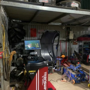 Máy cân mâm Omega 828Z Trainsway đỏ cùng các lốp xe ô tô xếp chồng.