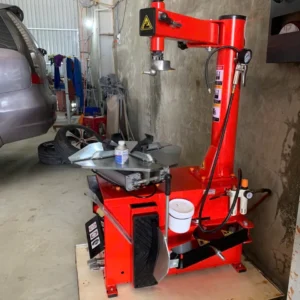 Máy tháo vỏ SUNTEK LP-930 (Khóa Hơi) đặt cạnh một chiếc xe ô tô trong gara, minh họa kích thước và không gian sử dụng.